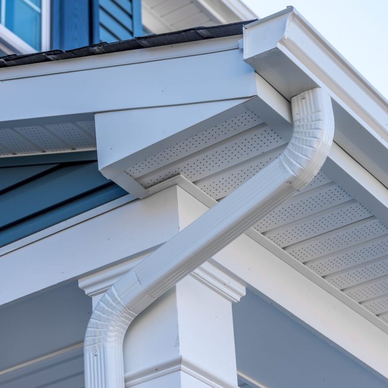 Colonial white gutter guard system, fascia, drip edge, soffit providing ventilation to the attic, with pacific blue vinyl horizontal siding at a luxury American single family home neighborhood USA